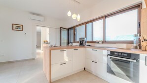 A modern kitchen with a built-in oven, a coffee maker, and a large window providing natural light. - Lovely home in Jovici (Jovici)