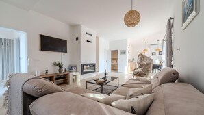 A modern living room with a large sofa set, a flat-screen TV, and a dining area with wicker chairs. - Lovely home in Jovici (Jovici)