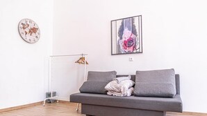 Una sala de estar moderna con un sofá gris, un reloj con mapa del mundo y un cuadro abstracto enmarcado.