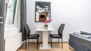 A room with a white table, two black chairs, a bed, a window, and a framed artwork on the wall. - Lovely Room @2nd Vienna, Only 10-Min to Augarten (Vienna)