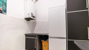 A compact kitchen with a refrigerator, a small cabinet, and a laundry basket. - Lovely Room @2nd Vienna, Only 10-Min to Augarten (Vienna)