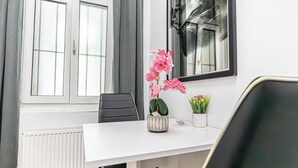 A white table with a vase of pink flowers, a potted plant, and a framed picture on the wall. - Lovely Room @2nd Vienna, Only 10-Min to Augarten (Vienna)