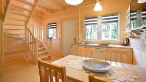 A wooden cabin interior with a dining area, kitchen, and a staircase. - Cozy home in Pobierowo with WiFi (Pobierowo)