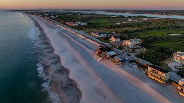 An aerial view of a coastal area with a beach, houses, and a bridge in the background. - Oceanfront Oasis w BBQ Pet Friendly Beach Access (Saint Augusitne)