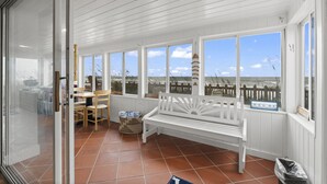 A covered patio with a white bench, a table with chairs, and a view of the ocean. - Oceanfront Oasis w BBQ Pet Friendly Beach Access (Saint Augusitne)