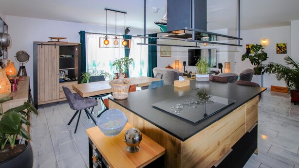 Una cocina moderna con una isla central, armarios de madera y un amplio ventanal con cortinas.