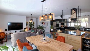 Un espacio habitable moderno con comedor, cocina y área de entretenimiento.