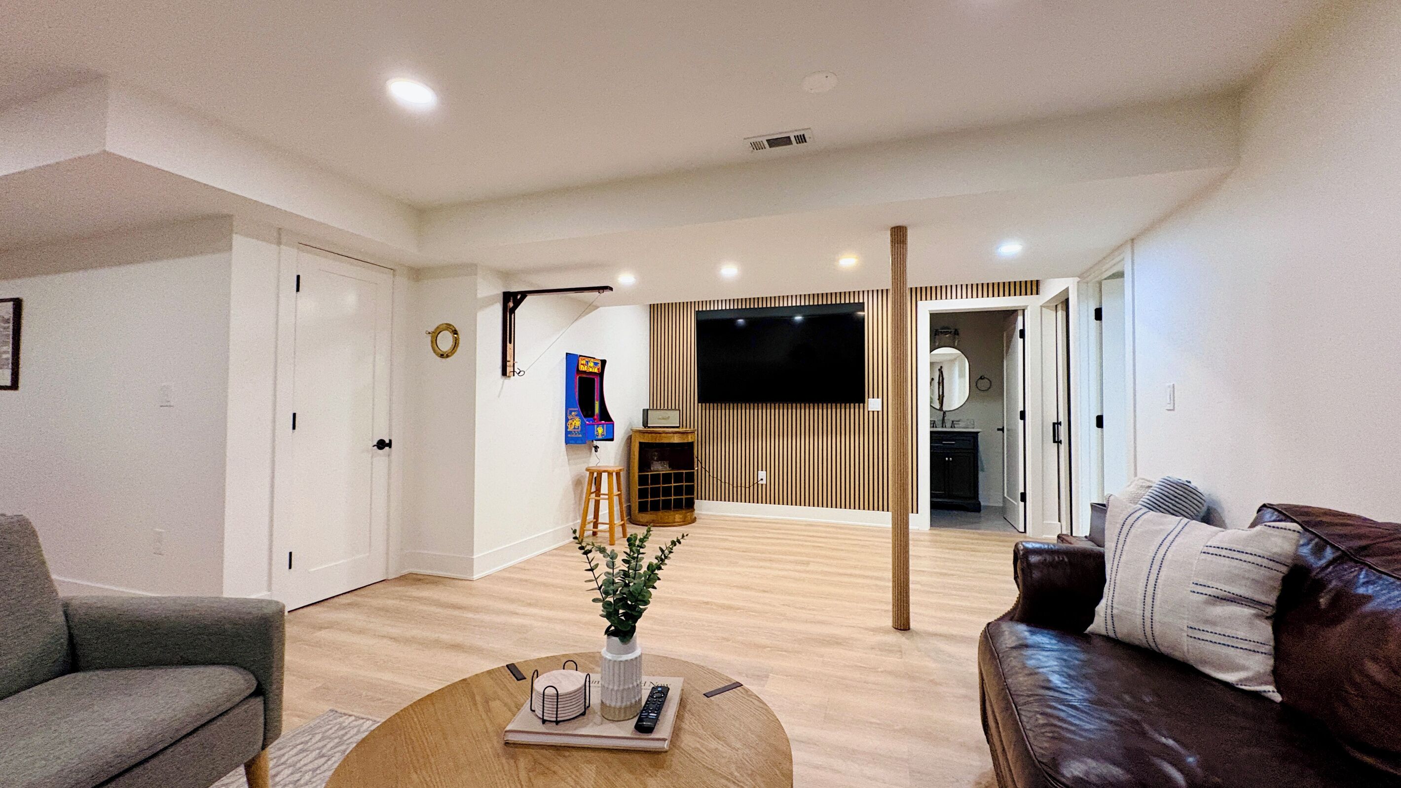 A modern living room with a sofa, a coffee table with a plant, and a TV mounted on the wall.