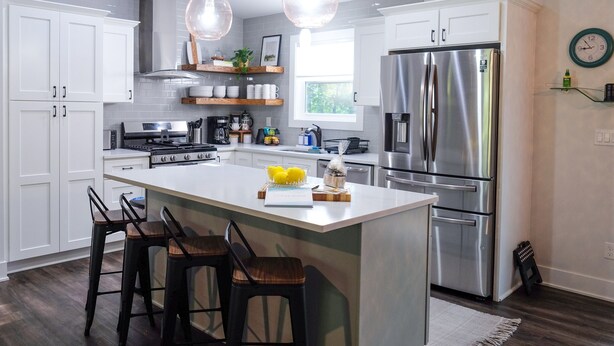 A modern kitchen with white cabinetry, stainless steel appliances, and a central island with bar stools.