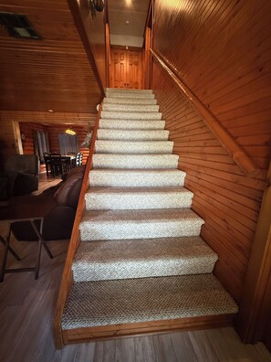 A wooden staircase with carpeted steps leading to a door at the top.