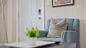 A modern living room with a blue sofa, patterned cushions, a small potted plant, and a framed picture on the wall. - 3 BR Cozy Home Near Indy Downtown , Foosball Table (Indianapolis)