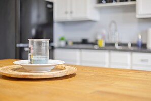 Eine Küche mit weißen Schränken, einer Holz Arbeitsplatte und einer klaren Glaskanne auf einem weißen Teller.