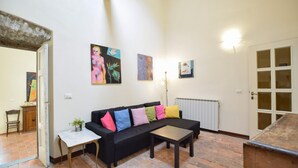 A living room with a black sofa, colorful cushions, a small table, and artwork on the walls. - Gorgeous apartment in Pontremoli (Pontremoli)