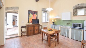 A spacious kitchen with a dining area, featuring a wooden table and chairs, a television, and a microwave. - Gorgeous apartment in Pontremoli (Pontremoli)