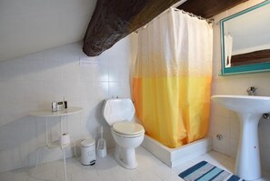 Une salle de bain équipée d’une baignoire, de toilettes, d’un lavabo et d’un rideau de douche.