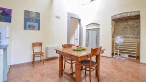 A dining area with a wooden table, chairs, a fruit plate, a radiator, and a stone wall. - Gorgeous apartment in Pontremoli (Pontremoli)