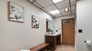 A hallway with a bench, a sink, and a door.