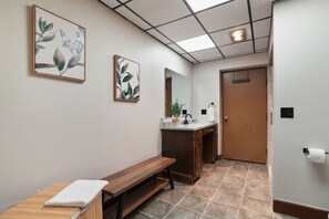 A hallway with a bench, a sink, and a door.