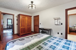 A bedroom with a bed, wooden wardrobe, desk, and chair.