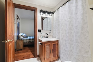 A compact bathroom with a wooden cabinet, a small sink, and a mirror.