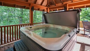 Uma banheira de hidromassagem em um deck de madeira com vista para árvores.