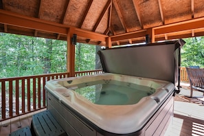 A hot tub on a wooden deck with a view of trees.