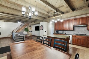 A spacious kitchen with wooden cabinets, a large island, and a dining area with a wooden table and chairs.