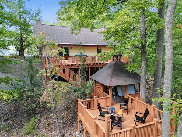 A two-story house with a deck, outdoor seating area, and a small gazebo.