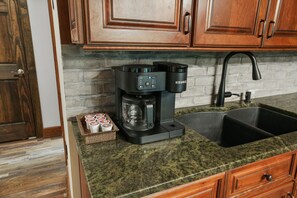 A kitchen with a Keurig coffee maker, a sink, and a tray of coffee cups.