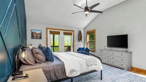 A bedroom with a bed, a desk, a chair, a television, and a ceiling fan. - Moose Shack - Mountain Views · Spa King Suite · Game Room · 3 Patios (Blairsville)