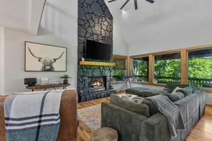 Una sala de estar moderna con chimenea de piedra, un televisor de pantalla plana grande y una zona de estar acogedora.