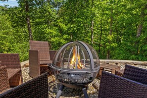 A fire pit with chairs around it, set in a forested area. - Moose Shack - Mountain Views · Spa King Suite · Game Room · 3 Patios (Blairsville)