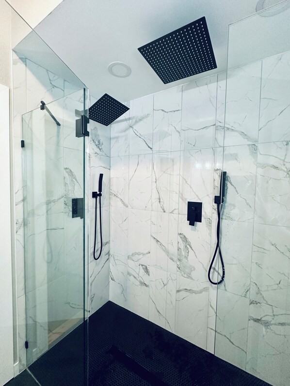 A modern shower room with glass doors, a rain shower head, and a handheld showerhead. - Moose Shack - Mountain Views · Spa King Suite · Game Room · 3 Patios (Blairsville)