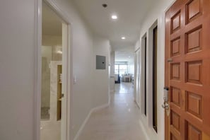 A hallway with a wooden door, a light switch, and a recessed ceiling light.