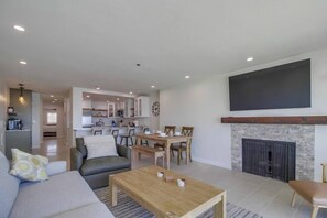 Un salon moderne avec une cheminée, un coin repas et une cuisine en arrière-plan.