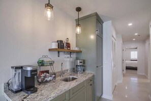 Une cuisine équipée d’une machine à café intégrée, d’une bouilloire et d’un meuble à vin.