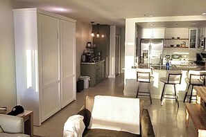 A modern kitchen with a refrigerator, stove, and dining area with chairs.