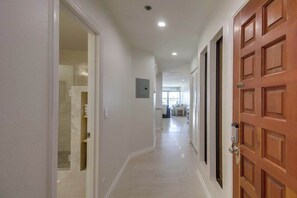 Un pasillo con una puerta de madera, un interruptor de luz y una lámpara en el techo.