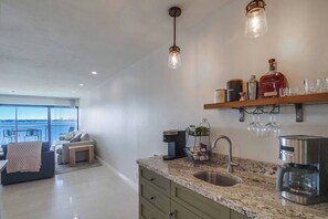 A modern kitchen with granite countertops, a coffee machine, and a view to the outside. - Bayfront 4th fl. balcony, parking, beach, bikes (San Diego)