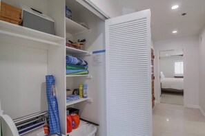 Un dressing avec des étagères, une tringle et un bac de rangement.