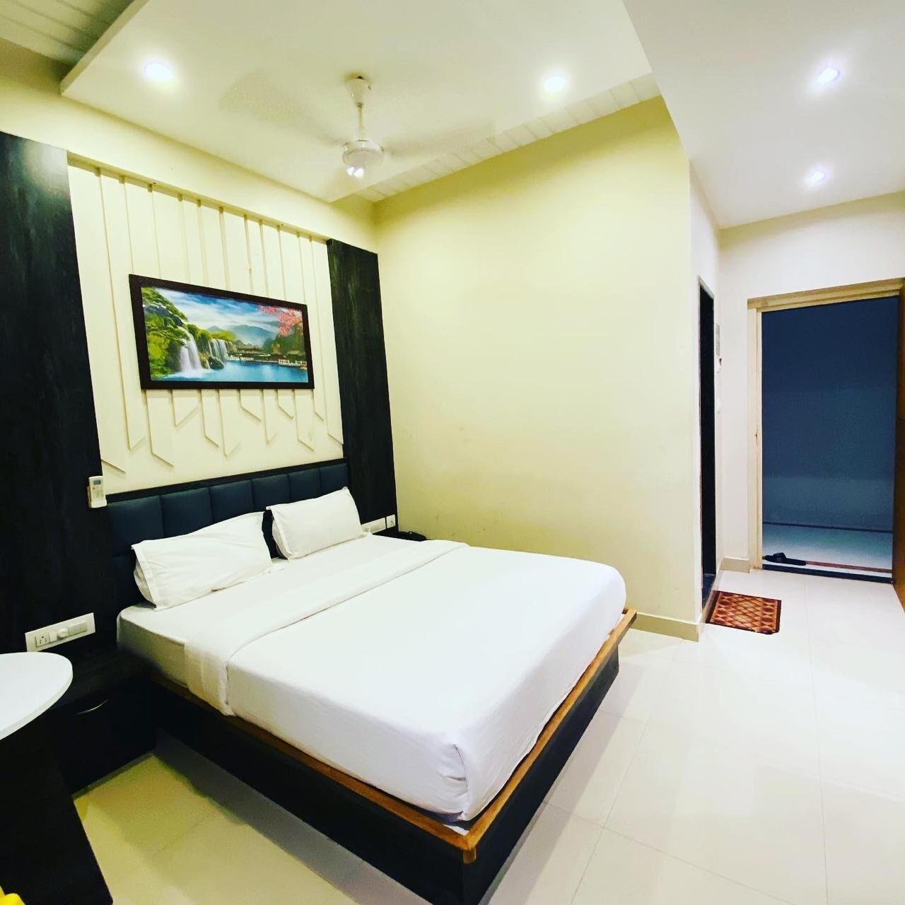 A modern hotel room with a large bed, a flat-screen TV mounted on the wall, and a ceiling fan.