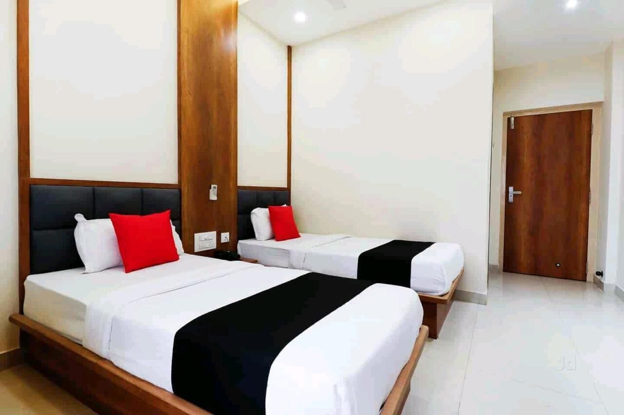 Habitación de hotel con dos camas, cada una con cubrecama blanco y negro y almohadas rojas y blancas.