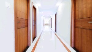 A hallway with wooden doors and a shiny floor. - HOTEL PLAZA AVENUE  (Mangaluru)