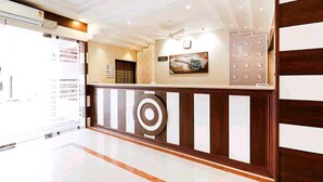 A reception area with a modern design, featuring a reception desk, a wall-mounted artwork, and a decorative panel. - HOTEL PLAZA AVENUE  (Mangaluru)