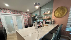 A modern kitchen with a marble countertop, a built-in stove, and a hanging light fixture. - Fun Open-Concept 2 Bedroom/2 Bathroom Condo w/Screened Porch. 10 Min from Disney (Kissimmee)