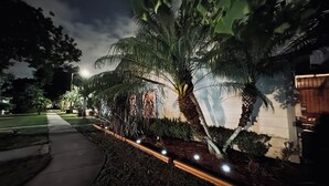 A nighttime view of a residential area with a well-maintained garden featuring palm trees and a pathway. - Fun Open-Concept 2 Bedroom/2 Bathroom Condo w/Screened Porch. 10 Min from Disney (Kissimmee)