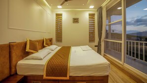 Una camera d'albergo con un letto, una ventola a soffitto e un'ampia finestra vista all'esterno.