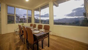 Zona pranzo con un tavolo grande apparecchiato per sei persone, ampie finestre che offrono vista sull'esterno e una scala visibile attraverso le finestre.