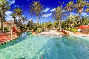 A clear pool with a 3 ft depth marker, surrounded by palm trees and a building with a red roof. - Spacious Townhome - 2 King Suites - Pool Access - No Resort Fees - Disney (Davenport)