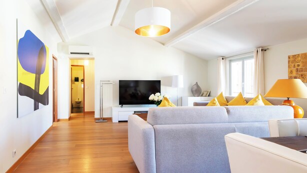 Un salon moderne avec un canapé gris, un téléviseur à écran plat et un coin repas comprenant une table et des chaises.
